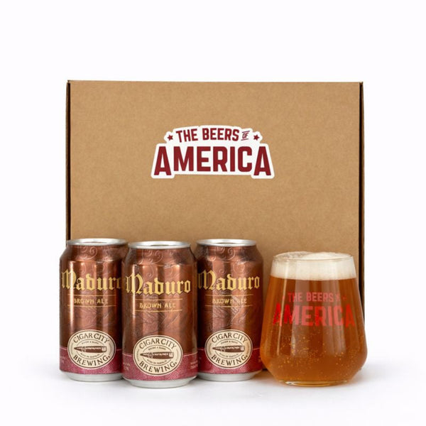 Three cans of Cigar City Brewing Co. Maduro Brown Ale and a glass of beer in front of a 'The Beers of America' branded box.